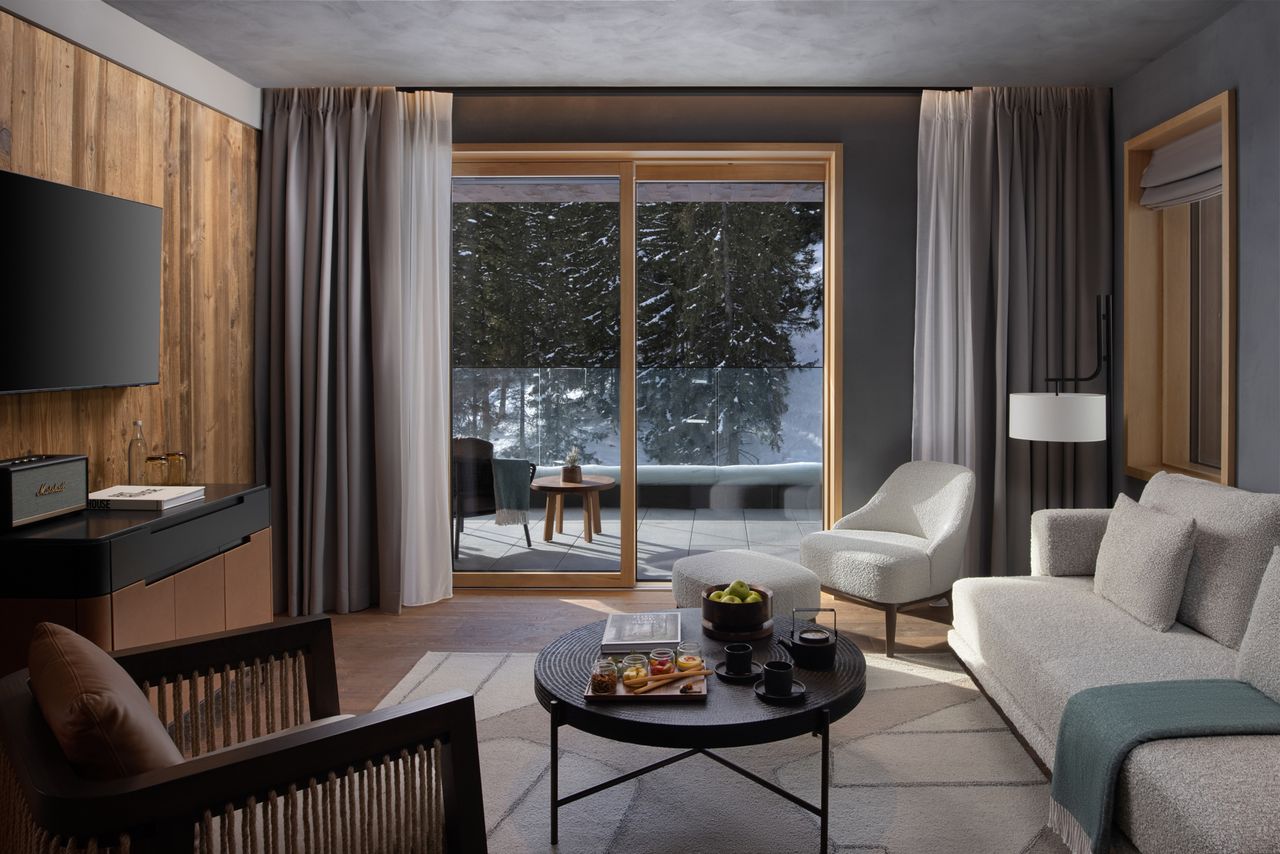 A cozy modern living room with a view through large windows of a snowcovered forest and a balcony