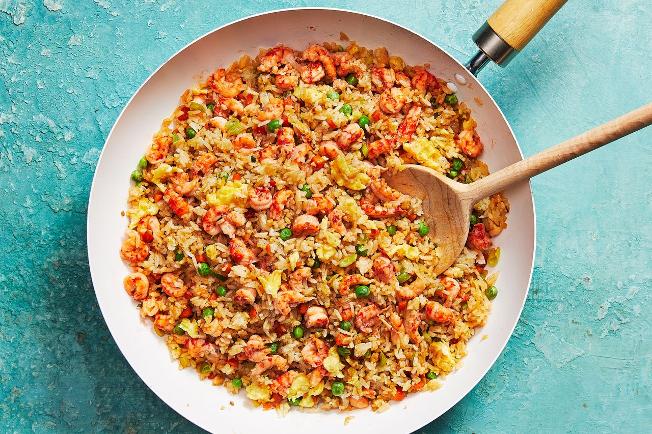 Crawfish fried rice in a pan with a wooden spoon.