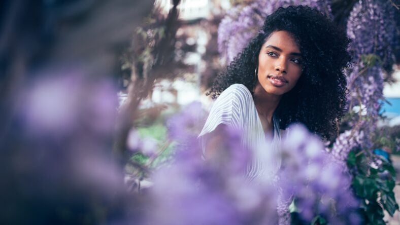 Young black woman sitting surrounded by flowers