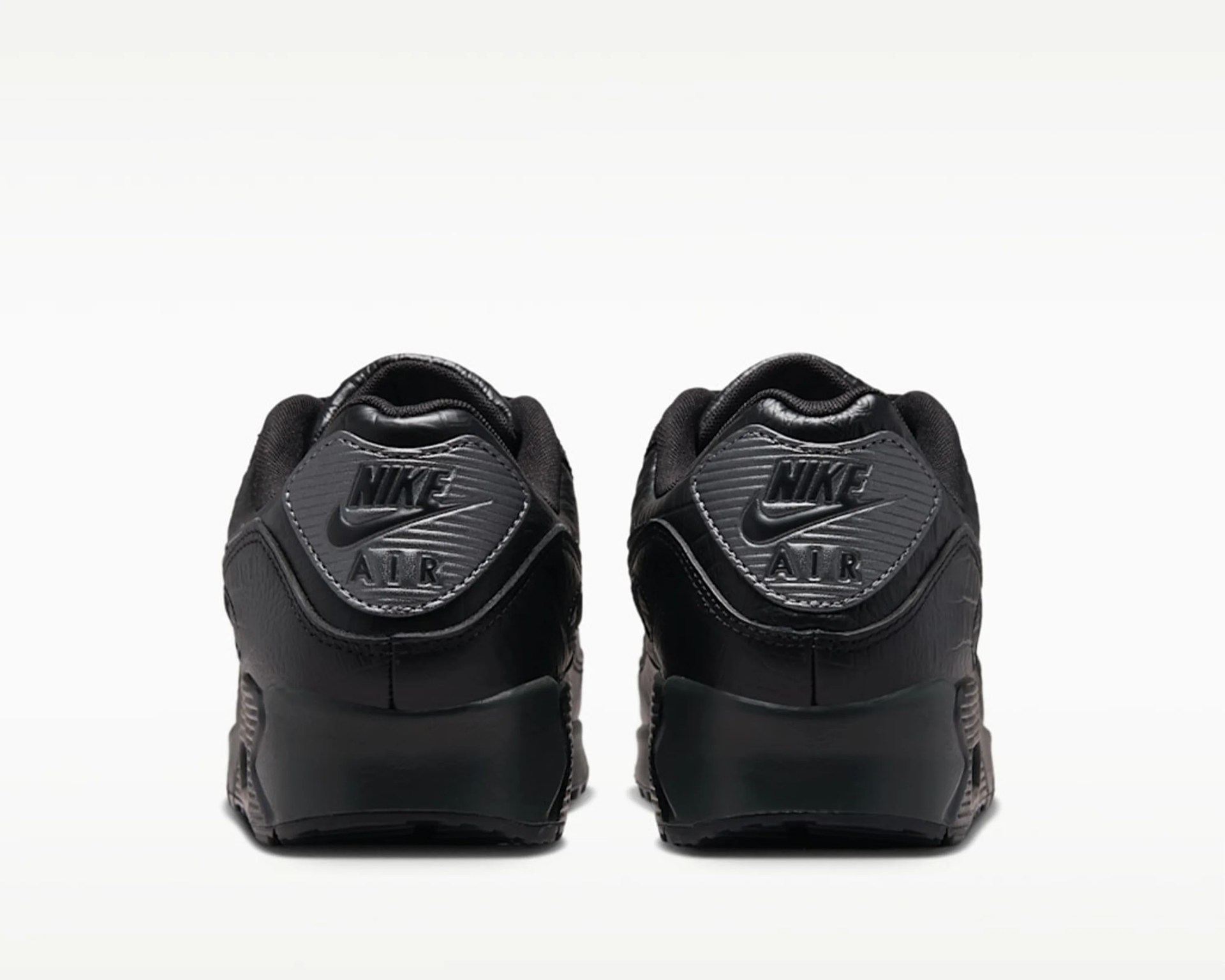 Pair of black Nike Air sneakers viewed from the back showing the Nike Air logo on the heel tab.