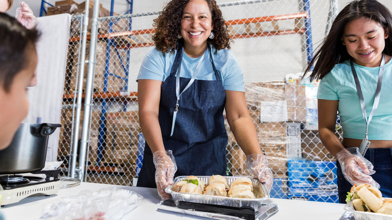Volunteer in apron holds sandwich tray
