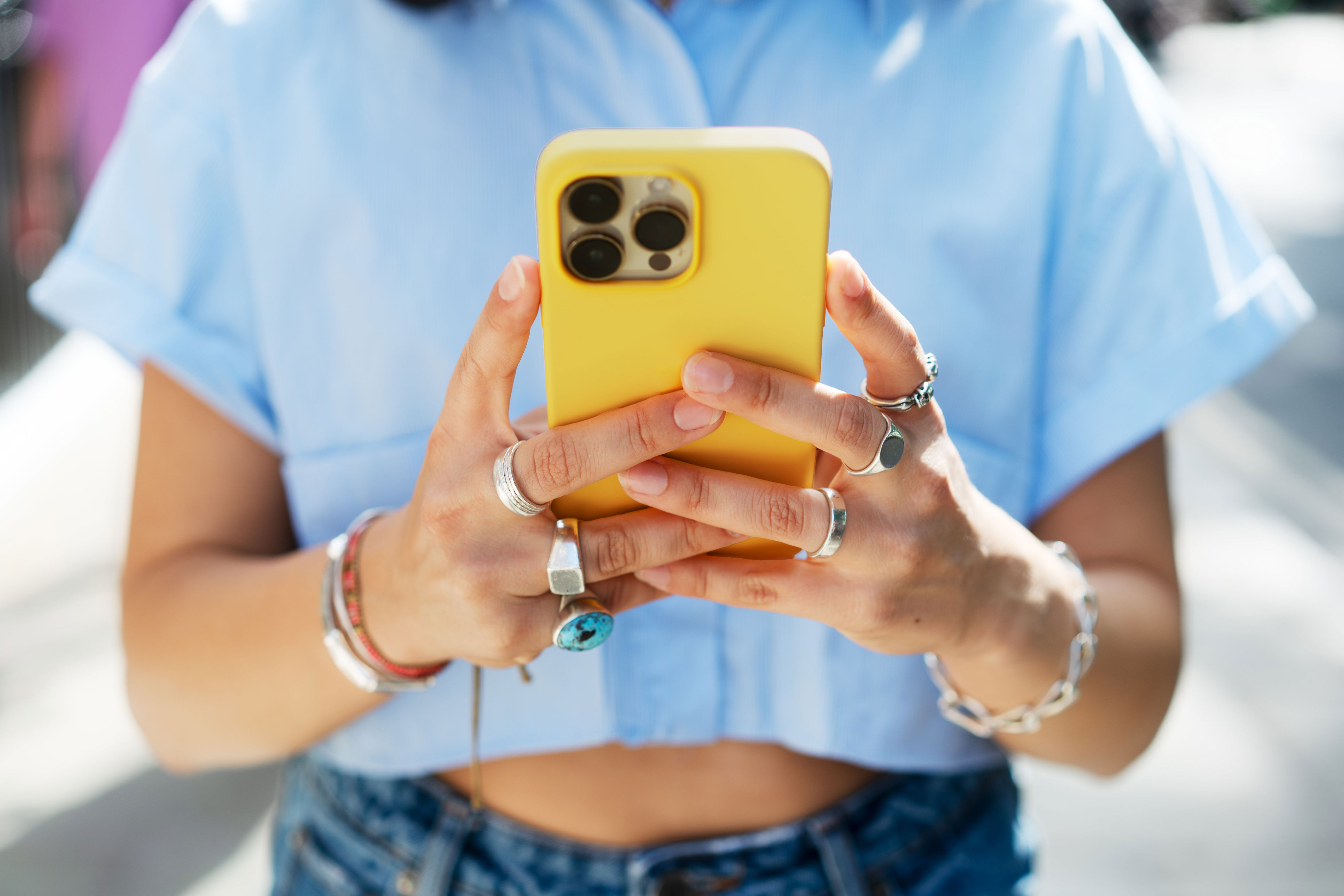A person in a casual outfit holding a smartphone