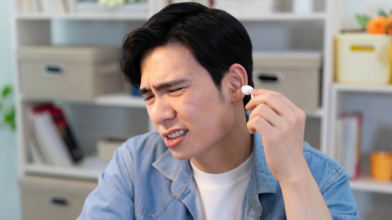 A man experiencing discomfort from his headphones