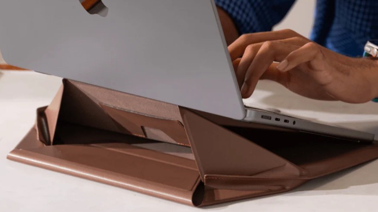 A man typing on a MacBook on a stand