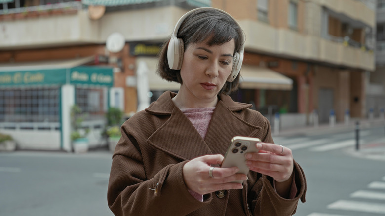 A woman adjusting headphone settings via smartphone app