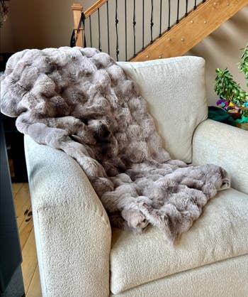 Luxurious faux fur throw draped over a plush chair in a cozy setting, suggesting warmth and comfort