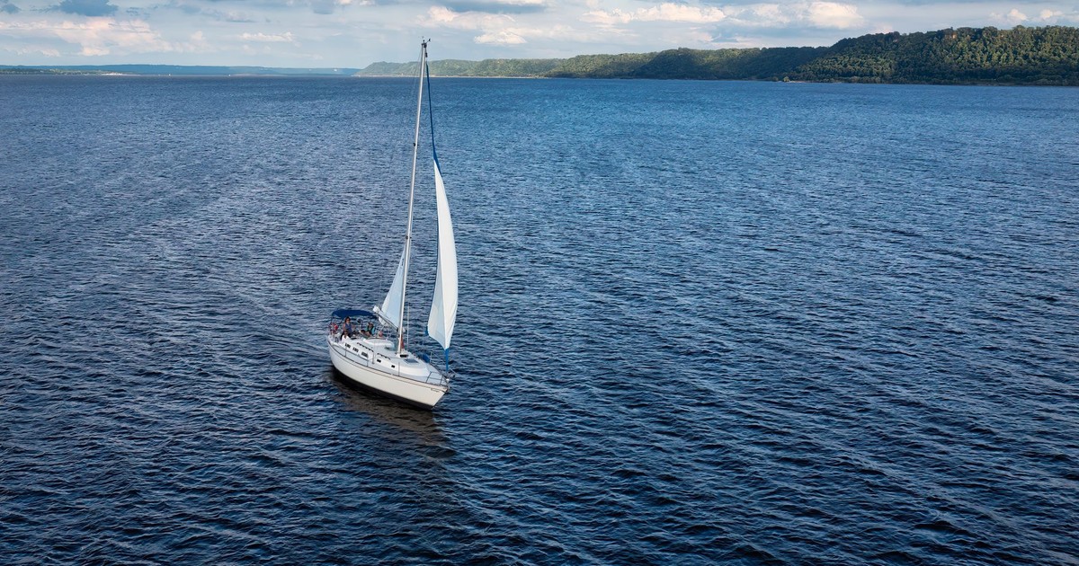 A sailboat on a calm lake under a bright summer sky, ideal for travel and nature themes.