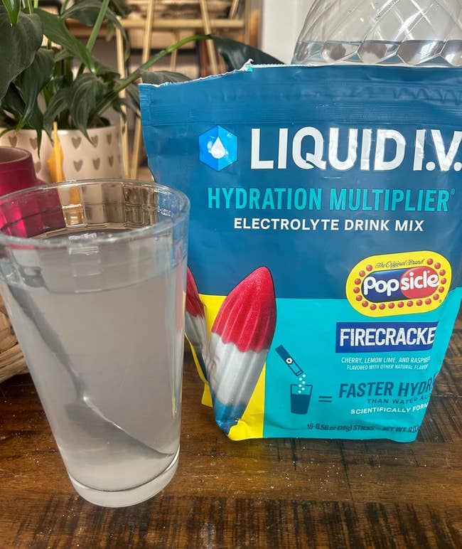 Reviewer image of glass with Firecracker Liquid I.V. mixed in next to the bag