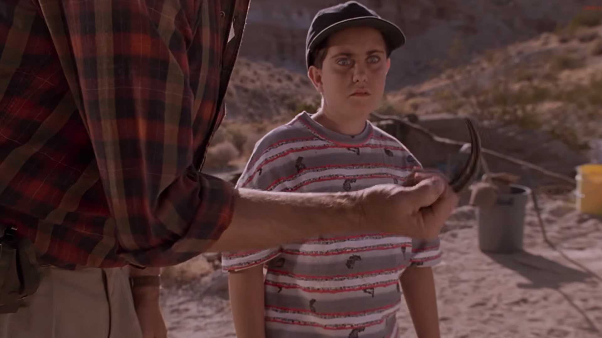 A kid looking terrified as Dr Grant shows him a raptor claw in Jurassic Park