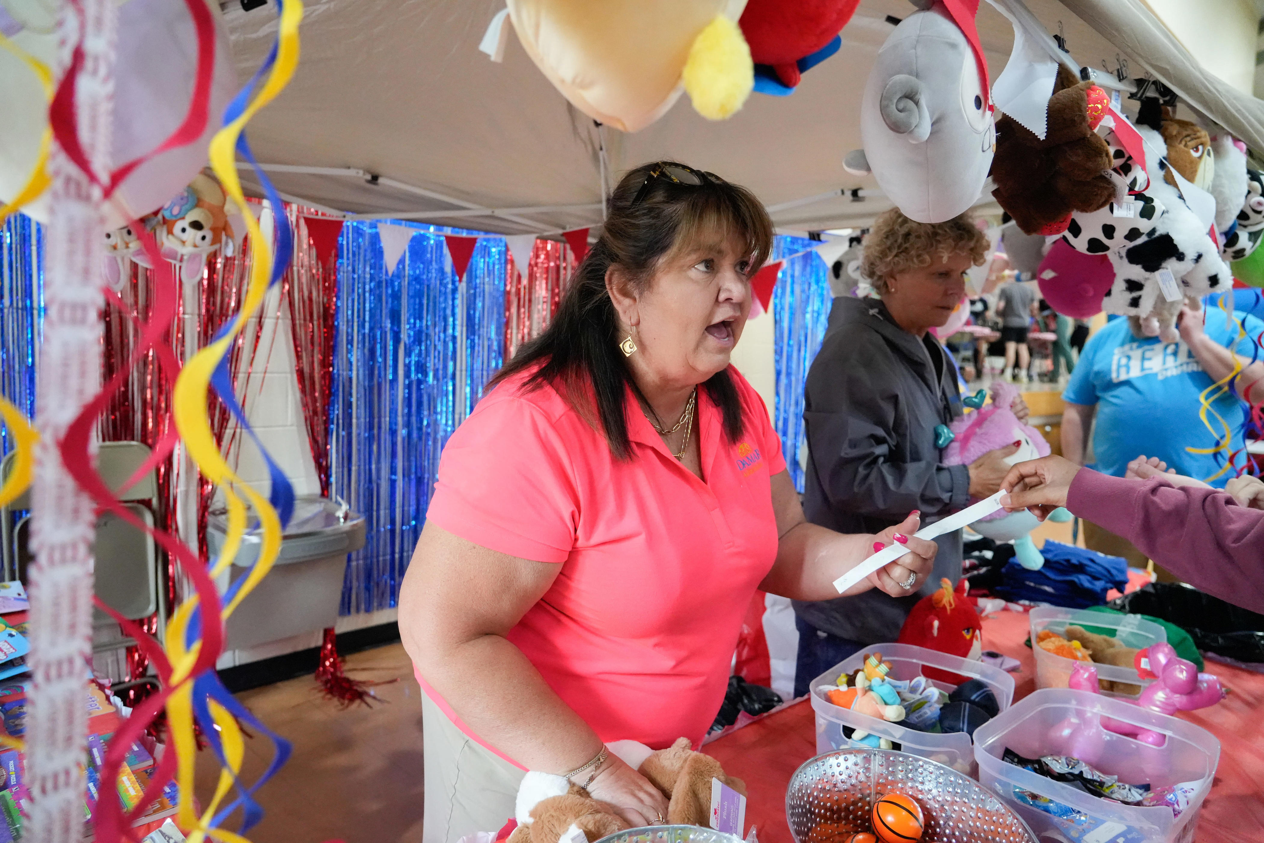 Angel Gehring, who has worked for Damar Services for 21 years, hands out prizes and stuffed animals during the fair day Thursday, June 25, 2026, at Damar Services in Indianapolis.
