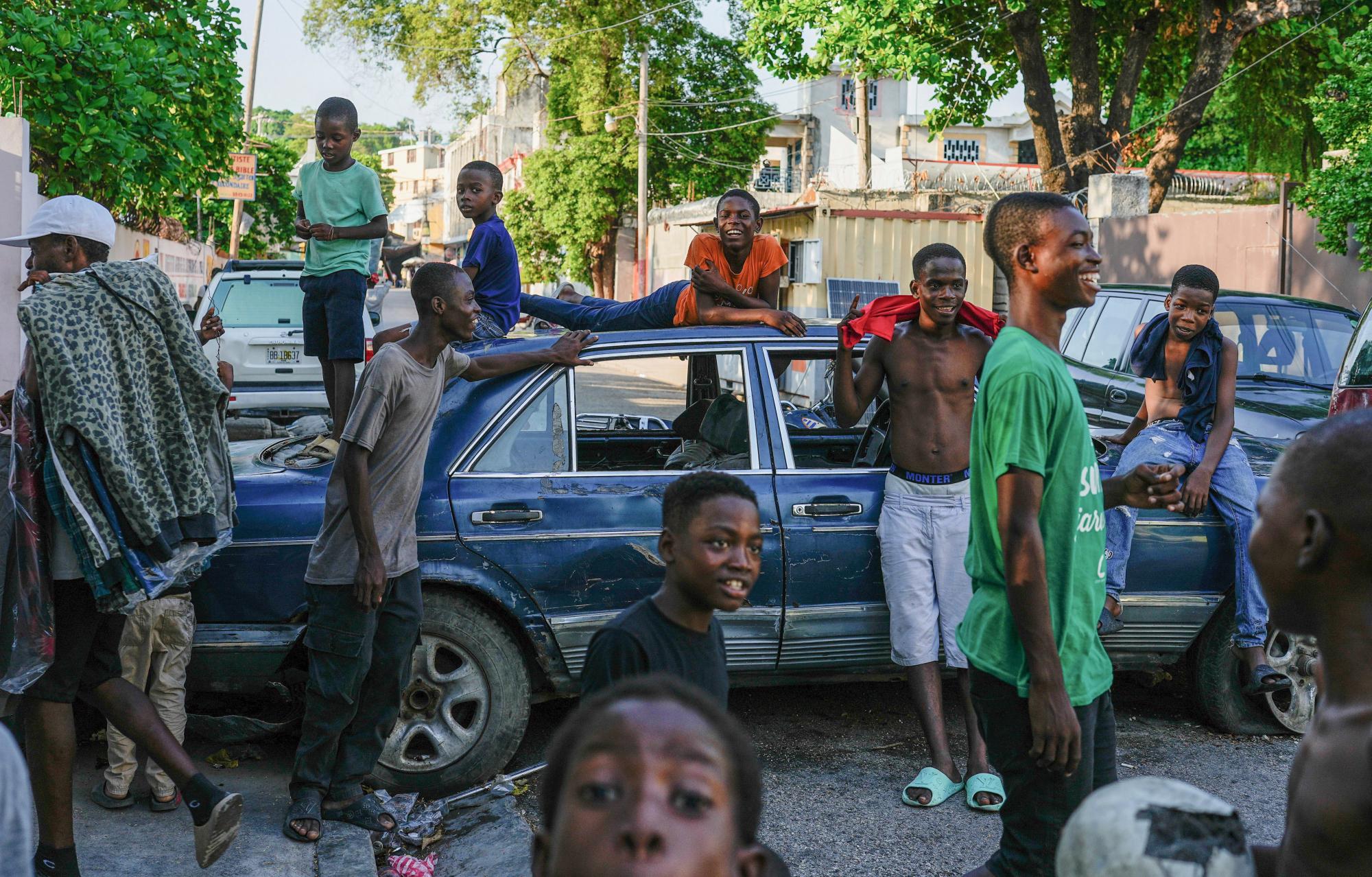 Youths in downtown Port-au-Prince near cars placed by residents as a barricade to deter the gangs from entering their neighbourhood, May 2024. Photograph: Ramón Espinosa/AP