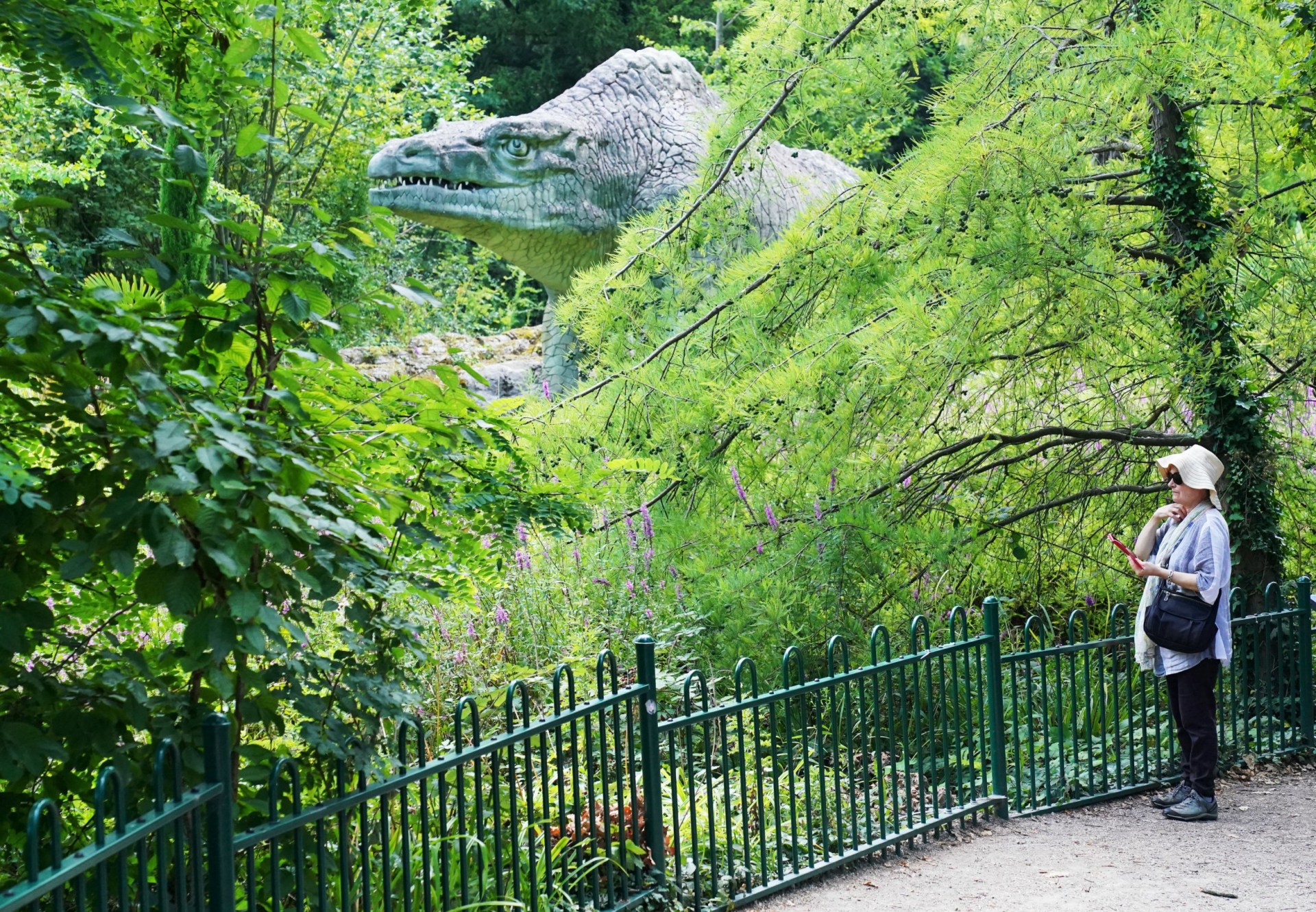 Visitors to Crystal Palace Park, London, observe a series of sculptures of dinosaurs.
