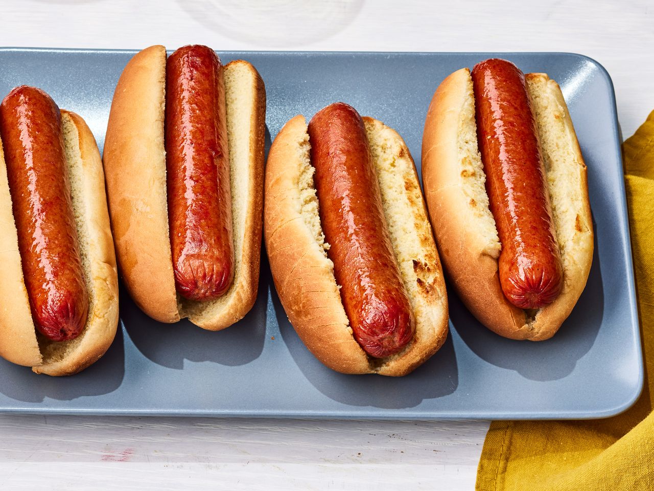 A platter with four hot dogs in buns