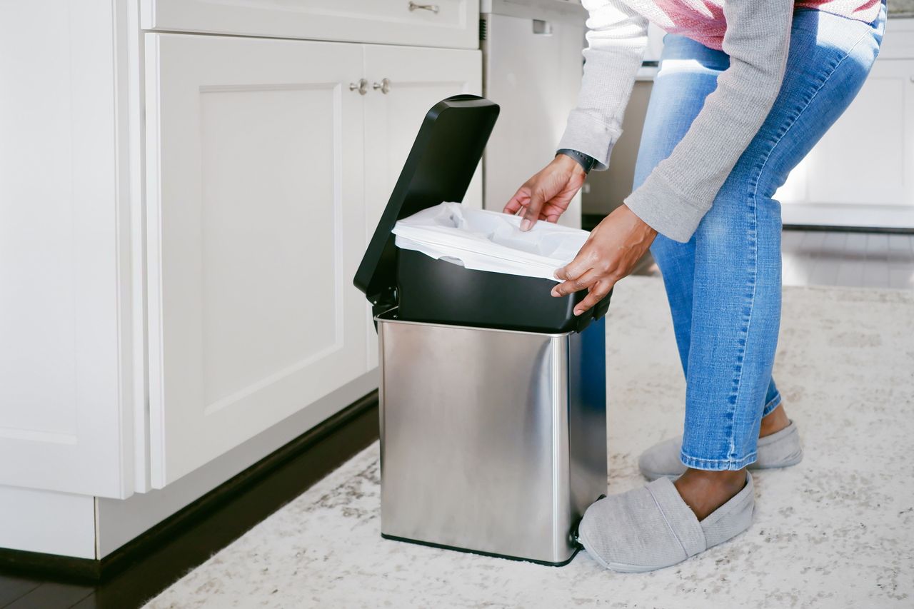person replacing trash bag in kitchen