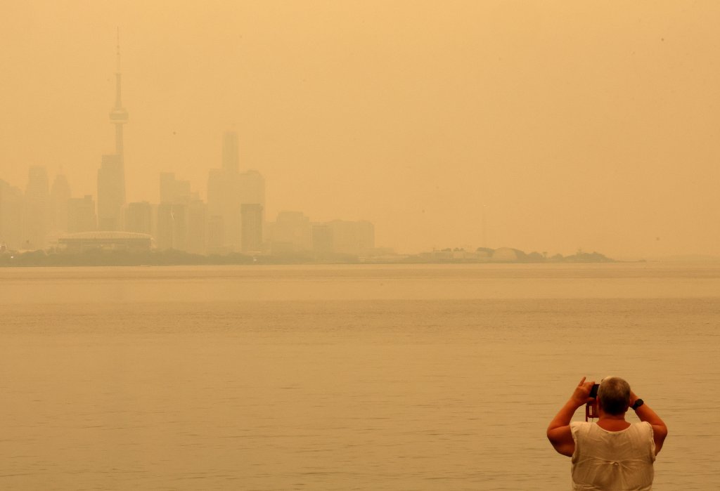 TORONTO, ON- JULY 15 - A person takes a photo as the view of the smoke from Northern Ontario forest fires that has the City of Toronto skyline shrouded in haze as viewed from Humber Park West in Toronto. July 15, 2026. Steve Russell/Toronto Star (Steve Russell/Toronto Star via Getty Images)