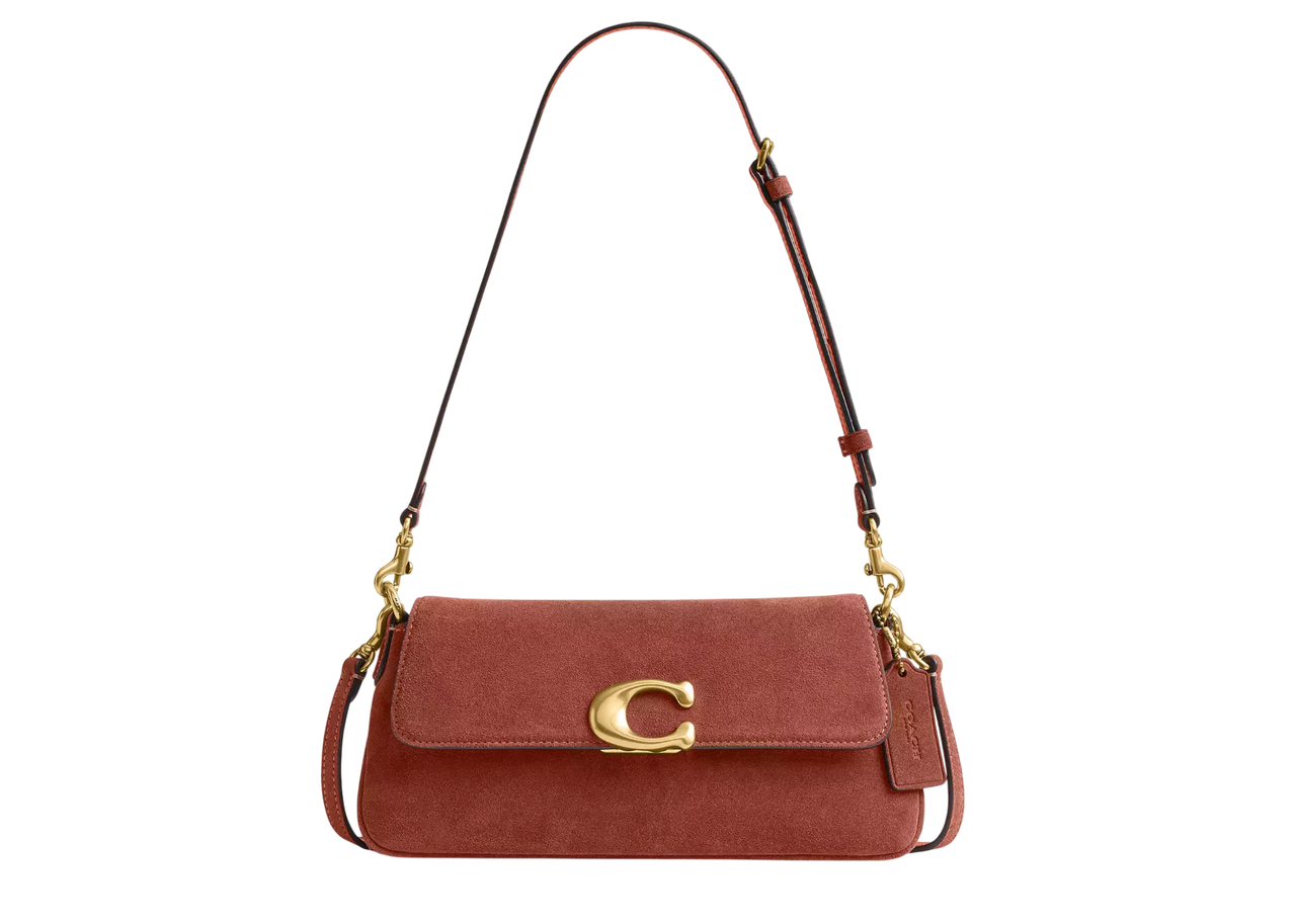 A leather handbag with a gold accent in the shape of the letter C on the clasp featuring a shoulder strap and a soft rectangular shape
