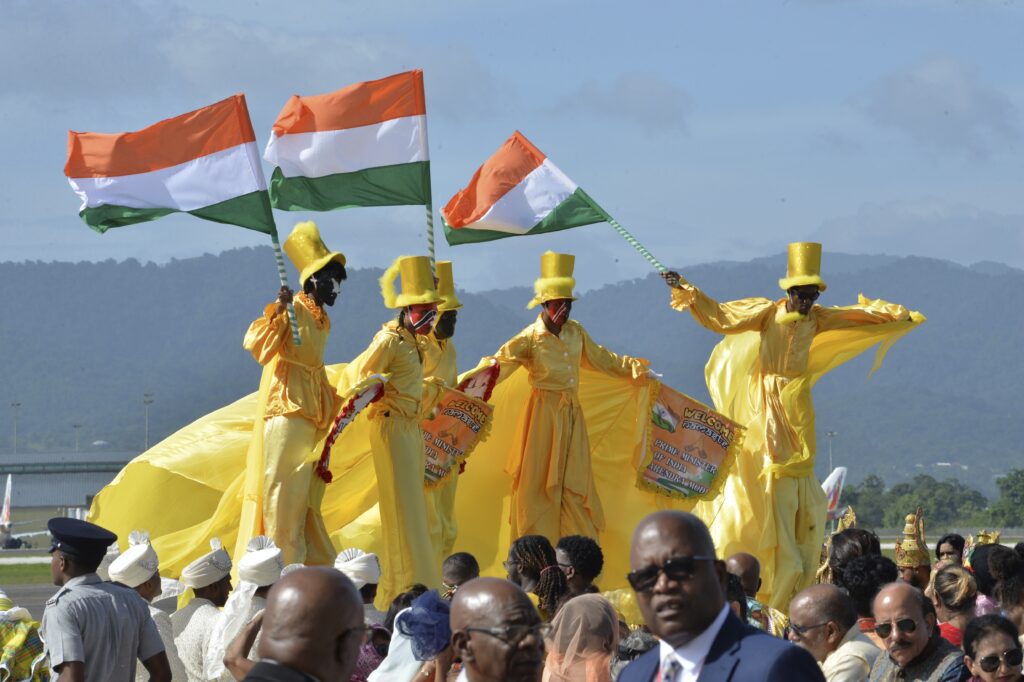 Stilt walkers in yellow costumes wave Indian flags and hold welcome banners for Prime Minister of India Narendra Modi at an airport arrival ceremony