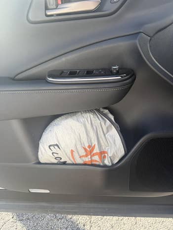 Plastic bag with a logo and text inside a car door compartment