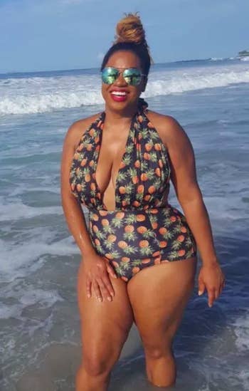 reviewer with sunglasses and hair bun standing in the ocean