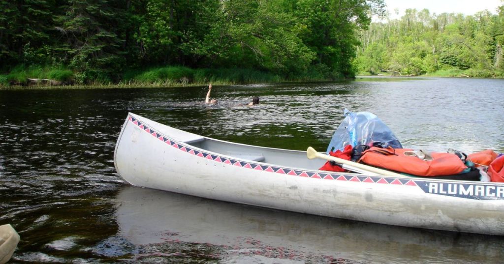 A canoe on the banks of Big Fork River in MN, surrounded by calm waters and lush greenery.