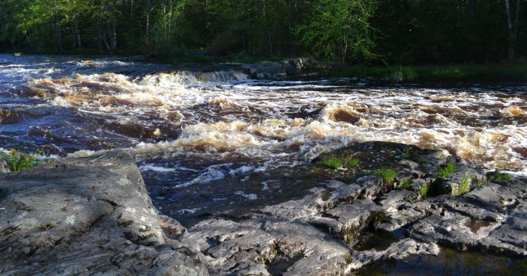 A natural water park in Minnesota, featuring water flowing over rocky terrain, surrounded by lush greenery.