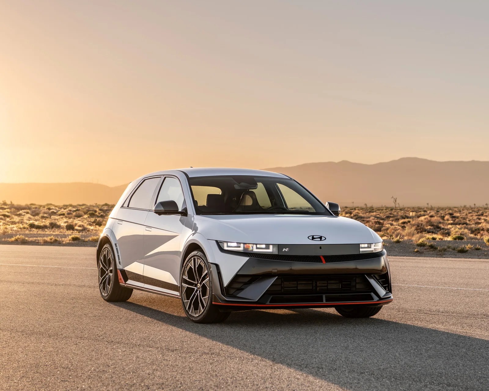 White Hyundai Ioniq 5 N electric hatchback with black and red accents parked on a desert road at sunset.