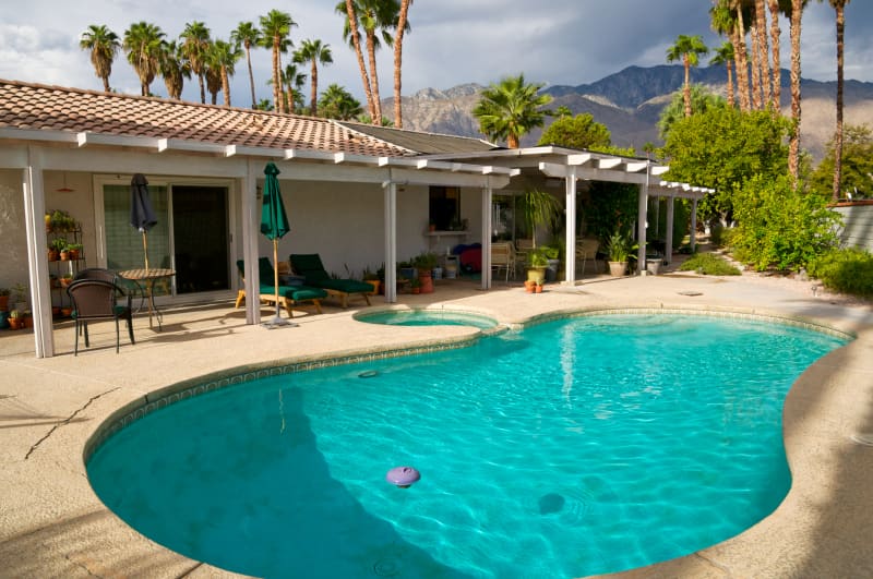 A dramatic, darkened cloudy sky is seen over the San Jacinto Mountains from a backyard pool of a Palm Springs home, Coachella Valley, Southern California, Western USA.