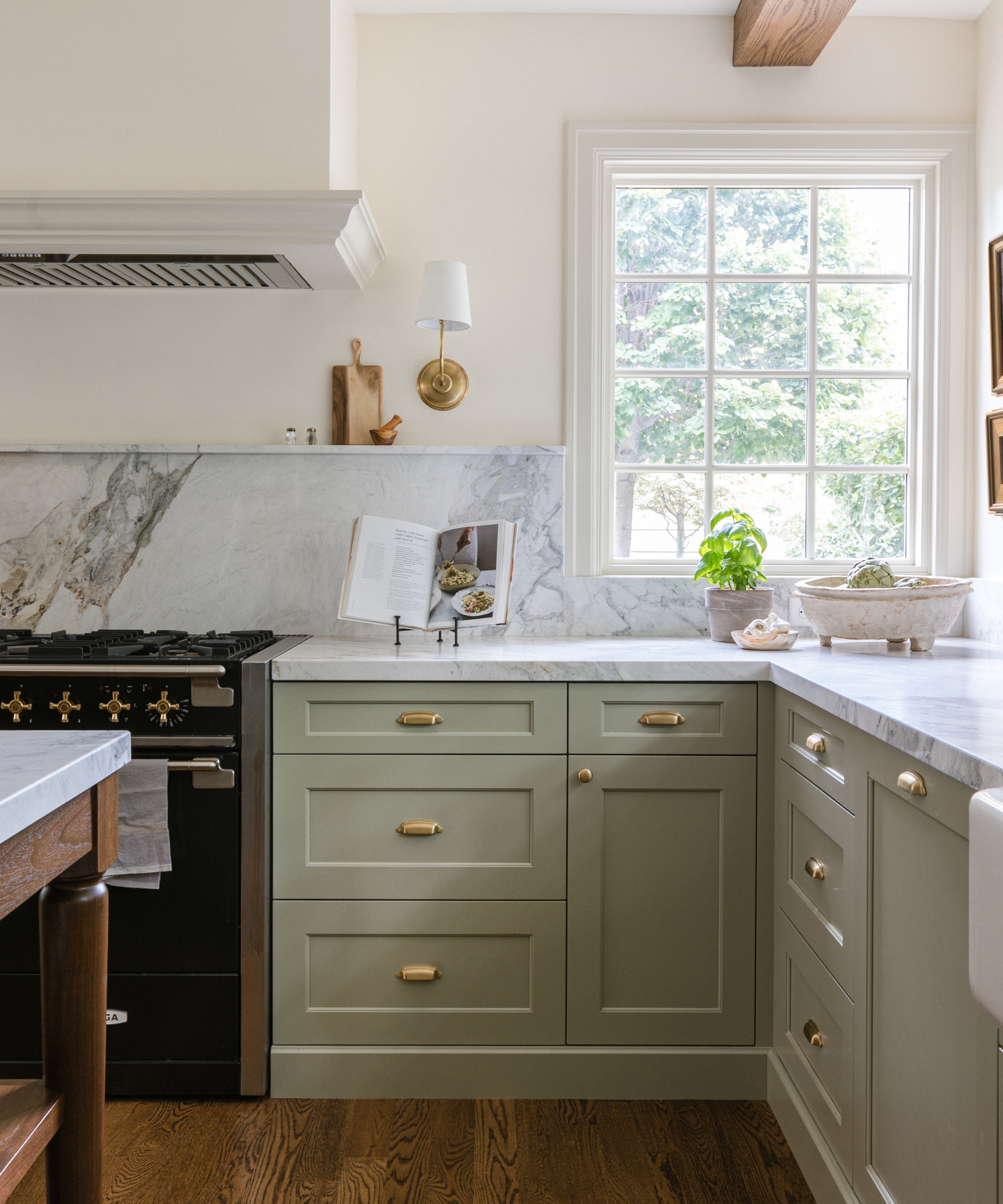A timeless kitchen with marble countertops, white walls, and cabinetry painted in French Gray by Farrow & Ball