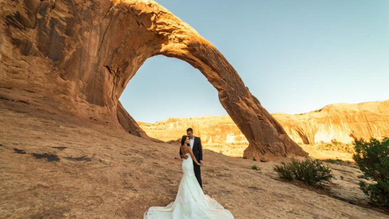 Asian/Vietnamese Bride with her Caucasian Groom. Wedding/Engagement photo under the beautiful Corona Arch at sunset in the Utah desert near Moab.