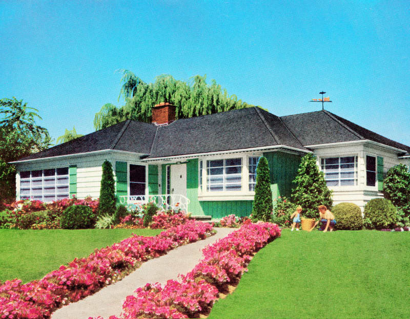 1950's green house with white trim with green lawn, pink azaleas. Mother and child outside with a large orange bucket