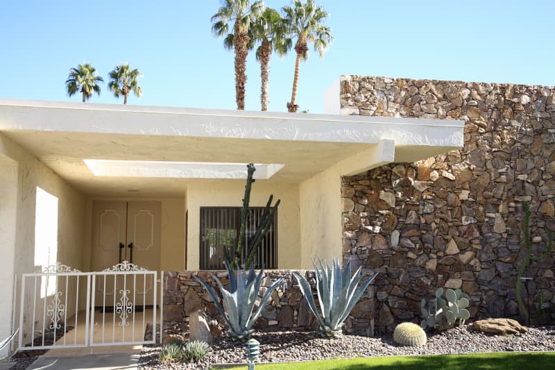 Front entrance and exterior view of mid century architecture. A main feature is the stone on the one wall. Xeriscaped garden of cactus and succulents.