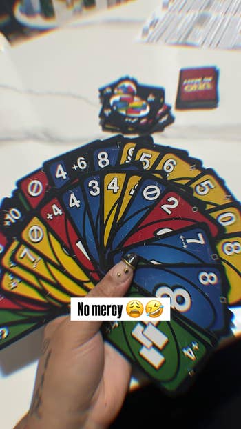 A hand holding a set of Uno cards