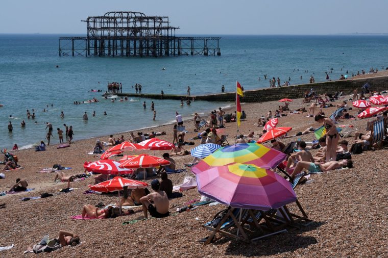 People enjoy the weather in the sea and on in the beach in Brighton, on the south coast of England on June 25, 2026, during a heatwave. The UK recorded its hottest ever June temperature on June 24 with the mercury rising to 36.1C in southern England, breaking the previous record of 35.6C set in 1976. (Photo by CARLOS JASSO / AFP via Getty Images)
