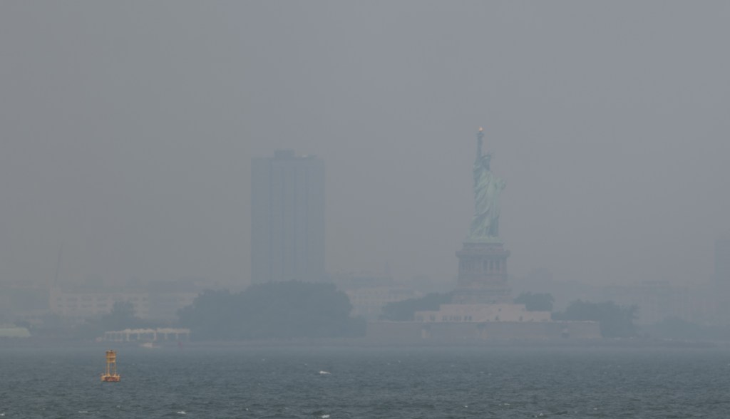 NEW YORK, NEW YORK - JULY 15: Haze from Canadian wildfires blankets the Statue of Liberty as seen from a Brooklyn pier on July 15, 2026 in New York City. New York City is under an Air Quality Health Advisory as the Canadian and Great Lakes wildfire smoke gradually moves through the area, creating a thick haze in the heat. New York City and much of the East Coast are experiencing temperatures with the heat index over 100 degrees as the region confronts another heat wave. (Photo by Spencer Platt/Getty Images)