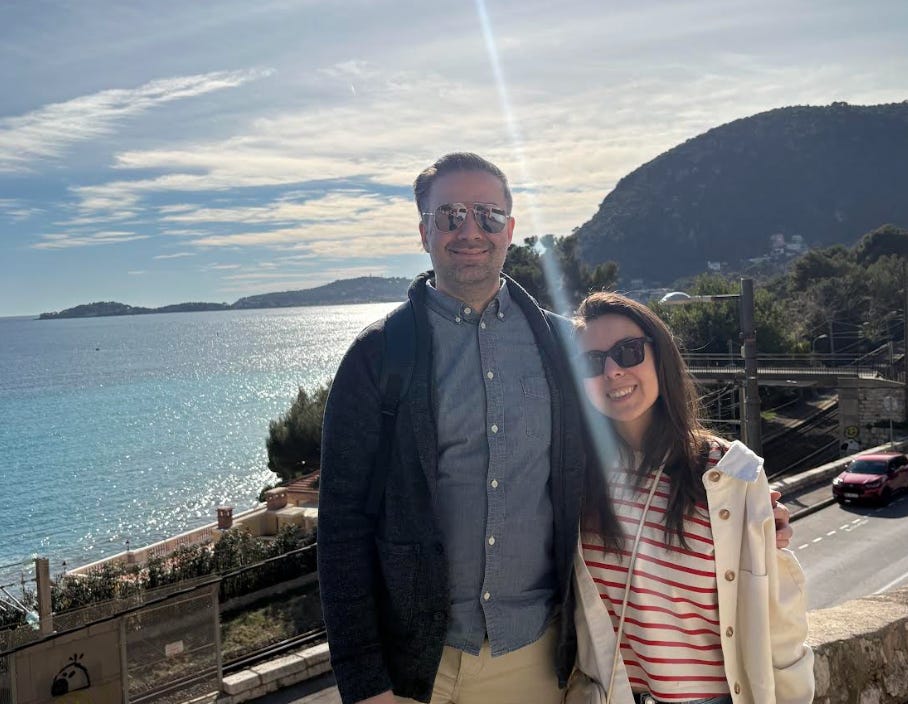 The writer and his partner standing in front of the water in France.