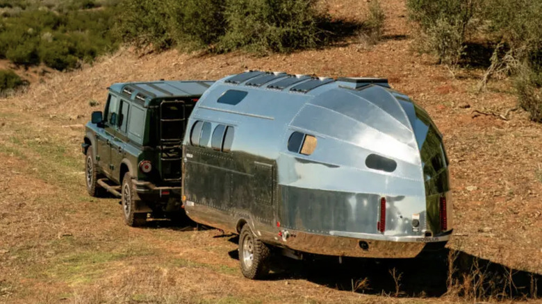 A Bowlus travel trailer being pulled by a Jeep Wranger on rugged terrain
