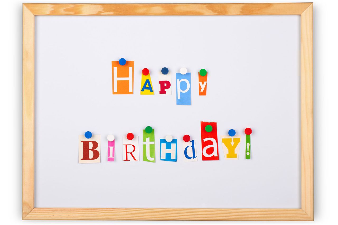 A framed magnetic board with colorful letters spelling Happy Birthday secured with magnets