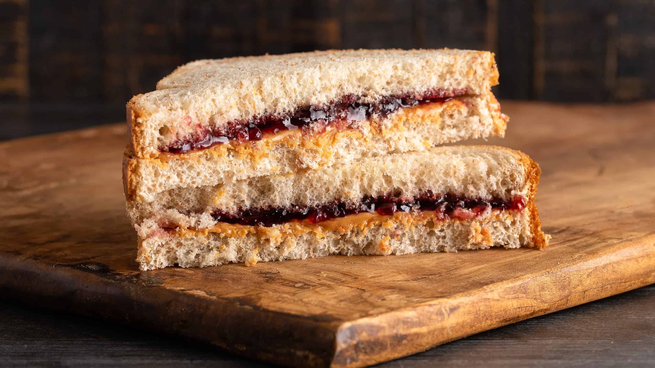 A Peanut Butter and Grape Jelly Sandwich on a Wooden Cutting Board