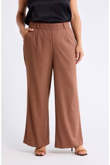 Person wearing wide-legged trousers with hands in pockets, styled with a sleeveless top, and heeled sandals. Casual yet chic fashion ensemble
