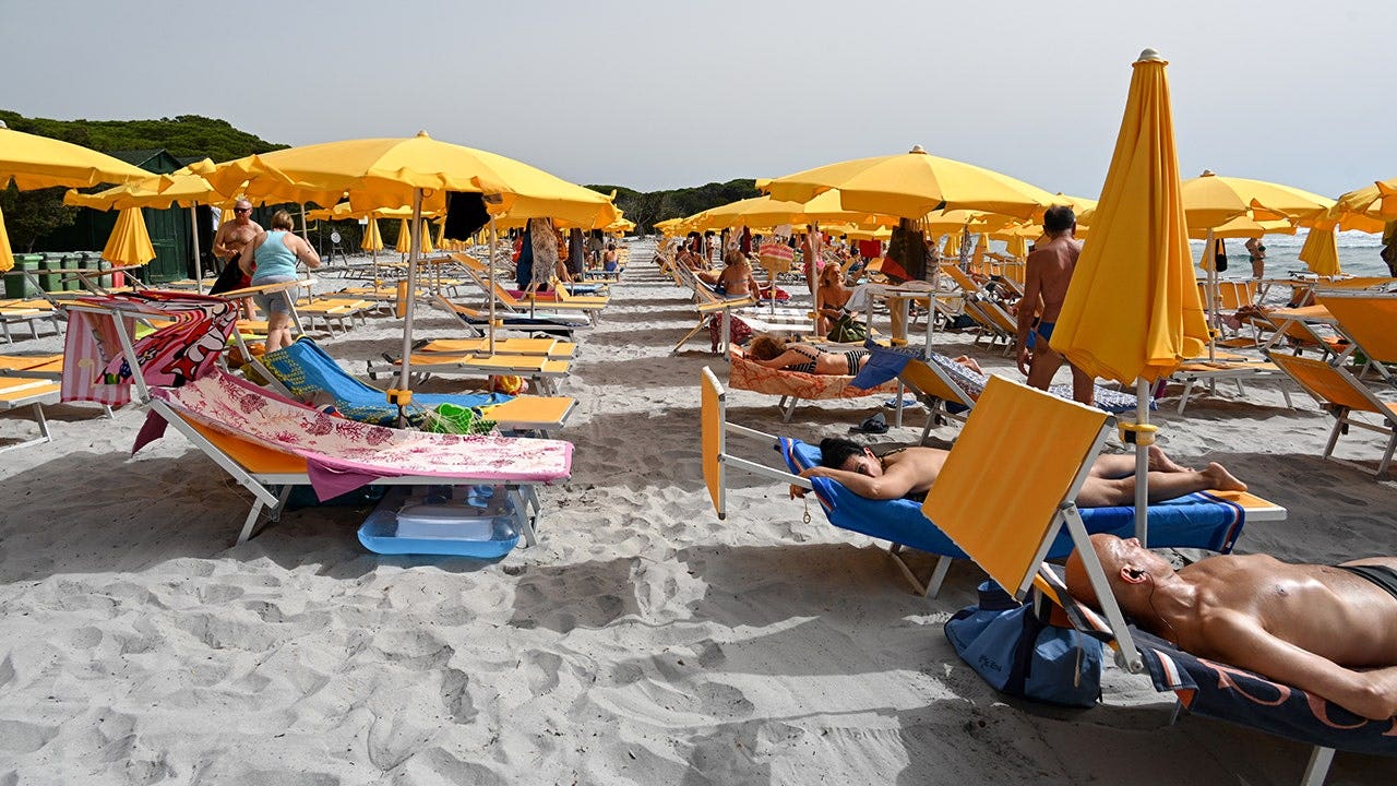 Tourists enjoy Cala Ginepro beach in Sardinia.