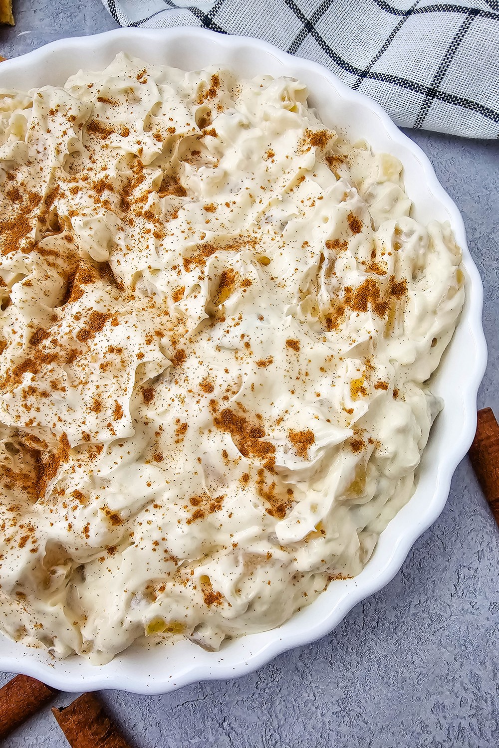 Overhead view of creamy apple pie dip dusted with cinnamon in a fluted white dish