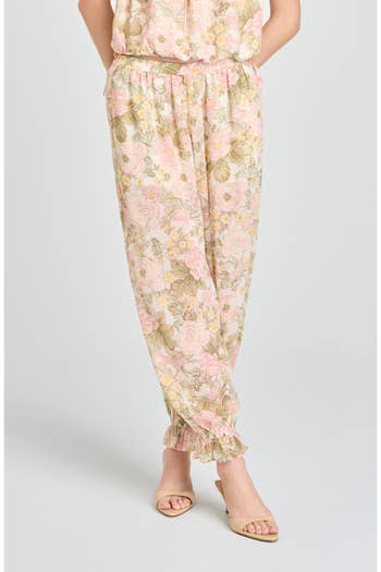 Person wearing floral print pants with ruffled cuffs and beige sandals, showcasing a casual spring fashion look