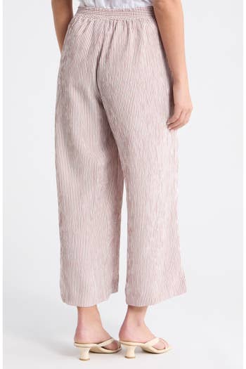 Model wearing striped, wide-leg pants and low-heeled sandals, viewed from behind. Outfit suitable for casual shopping