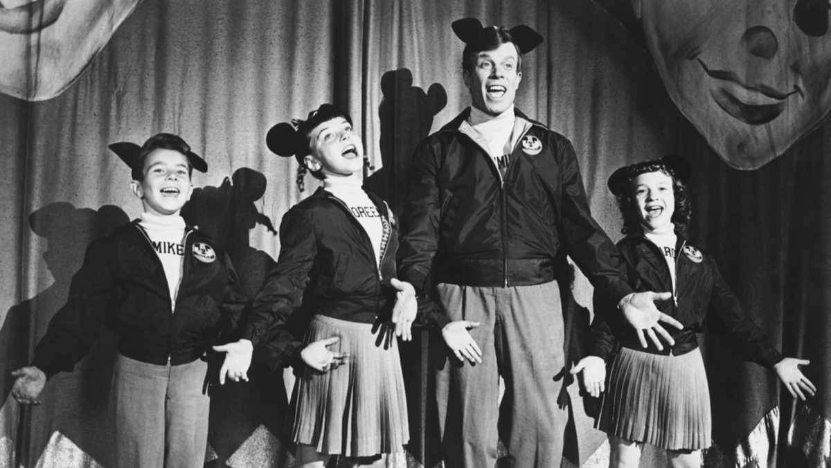 Sharon Baird, Jimmie Dodd, Michael Smith, and Doreen Tracey in The Mickey Mouse Club (1955) perform in Mouseketeer costumes during the show's first television run (Image Source: The Walt Disney Co.)