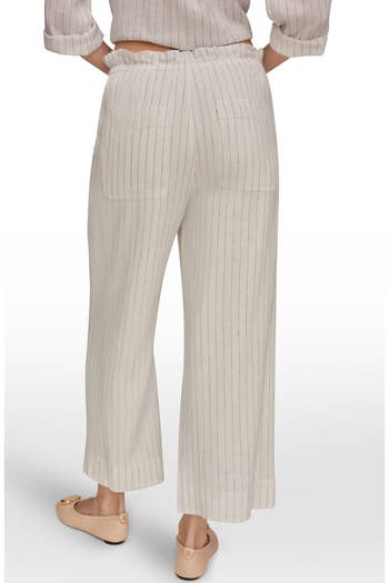 Back view of a person wearing pinstripe lounge pants and ballet flats