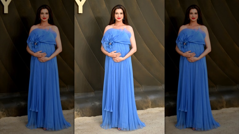 Anne Hathaway puts her hands on her bump in a blue gown