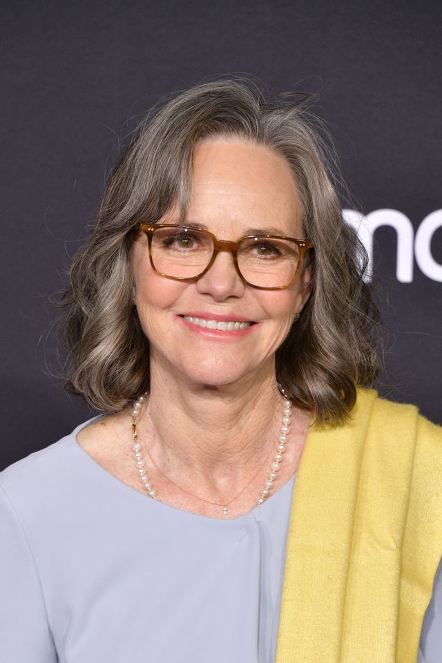 Sally Field smiling at an event wearing glasses and a light outfit