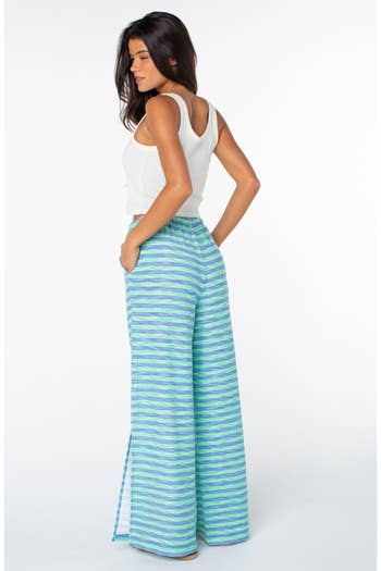 Woman wearing a sleeveless top and wide-leg striped pants, posing for a shopping article