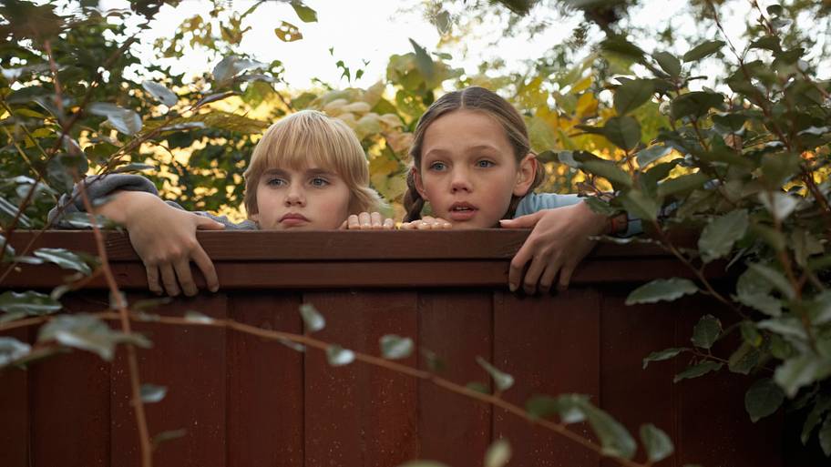 Boy and girl peeping over fence
