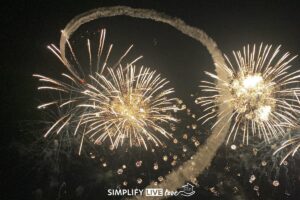 night airshow at eaa airventure oshkosh - fireworks and a plane contrail
